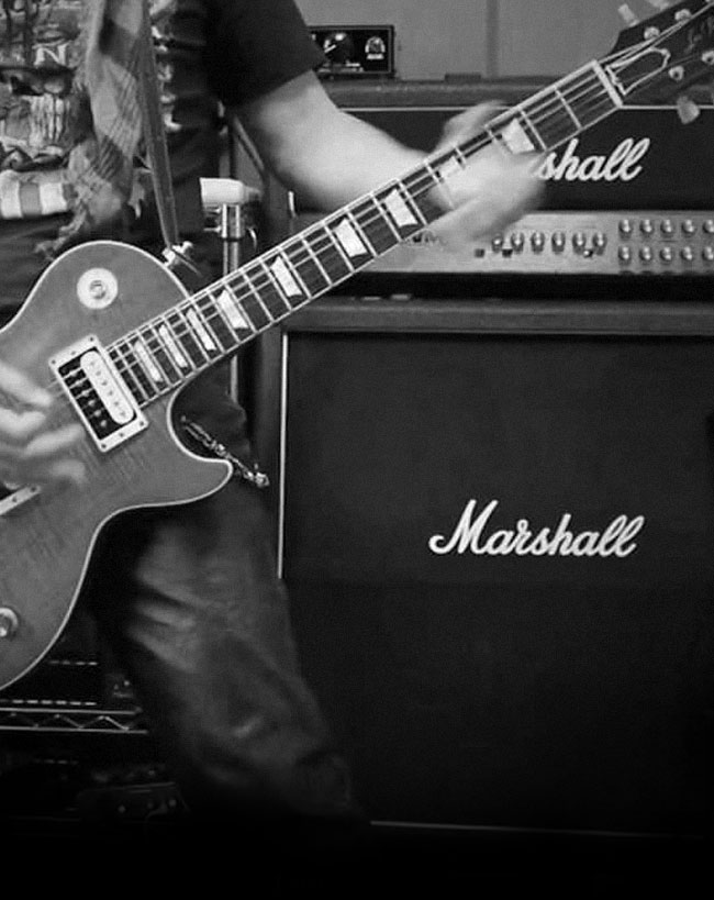 A guitarist playing in front of a Marshall Amp