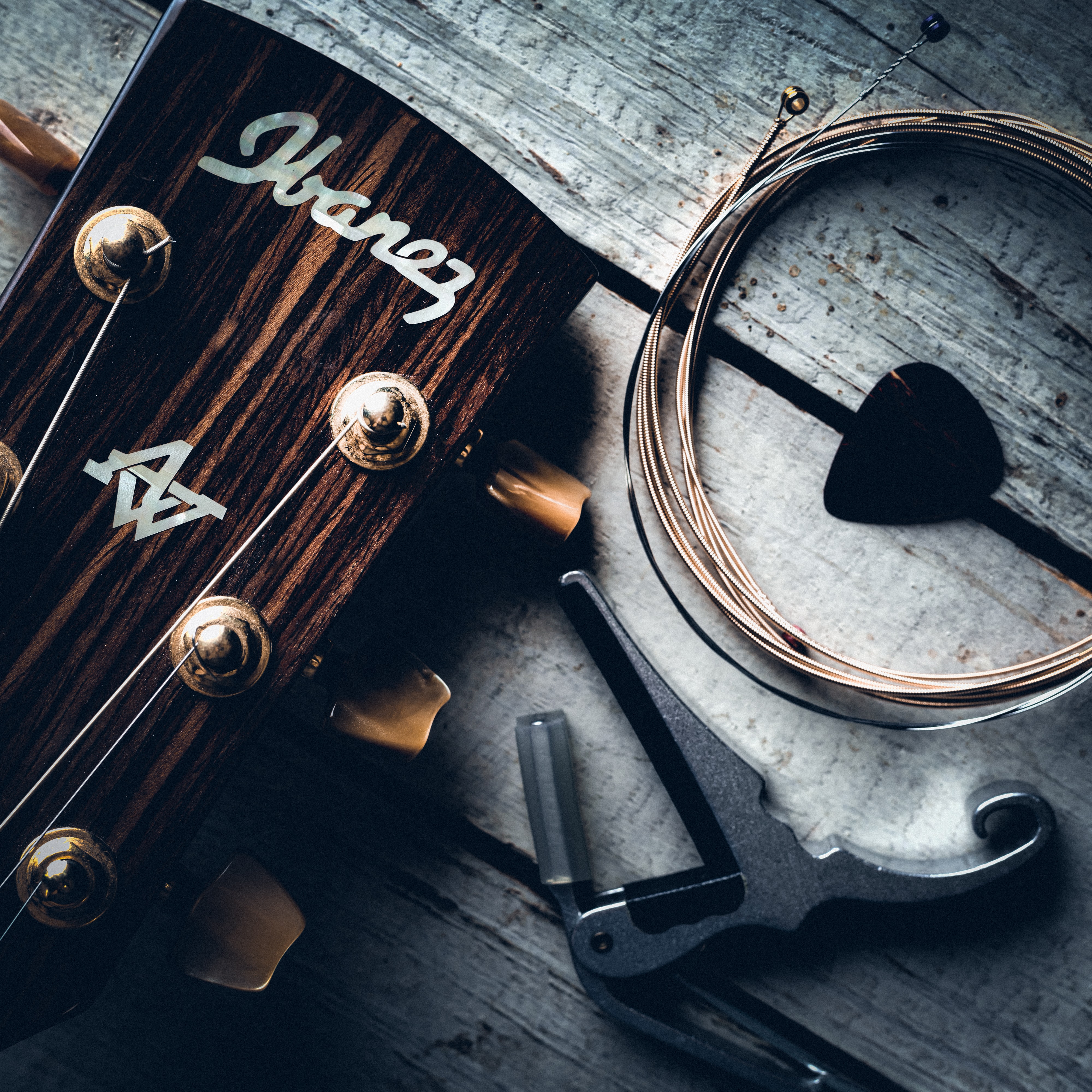 Close up of a Ibanez acoustic guitar headstock, a set of strings and a plectrum.