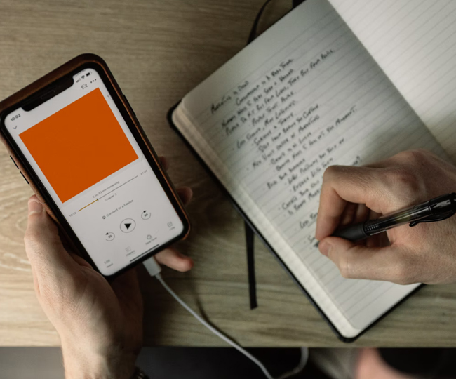 iPhone showing music on screen with hand writing in notebook