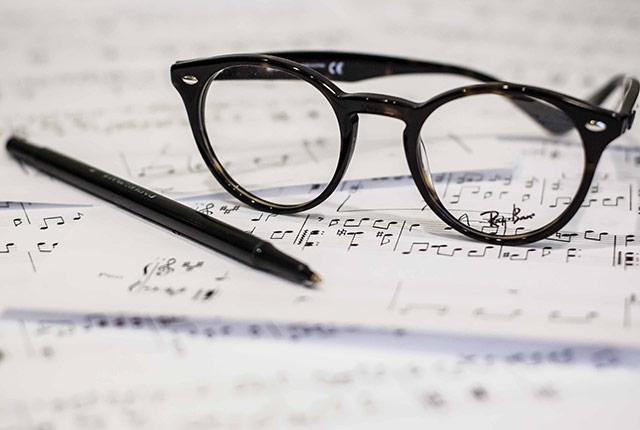 Glasses and pen lying on musical notation